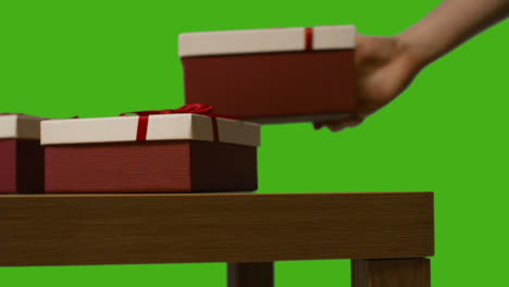 Nahaufnahme-Eines-Mannes,-Der-Verpackte-Geschenke-Auf-Den-Tisch-Legt,-Aufgenommen-Vor-Einem-Greenscreen